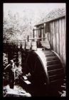 Man beside a water wheel. Black and white photo. 